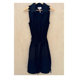 Vestido camisero negro sin mangas Laundry by Shelli Segal con cinturón, modelo de pie descalza sobre fondo cálido tipo chukum, estilo parisino de lujo relajado