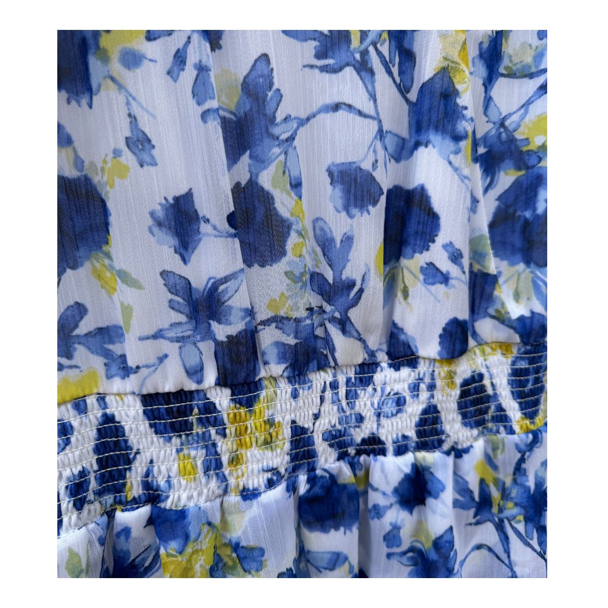 Vestido maxi floral en tonos oceánicos: capas de volantes vaporosos, estampado acuarela de flores índigo y amarillo sol sobre blanco puro. Cintura smocked y mangas flutter para un look cottagecore