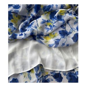 Vestido maxi floral en tonos oceánicos: capas de volantes vaporosos, estampado acuarela de flores índigo y amarillo sol sobre blanco puro. Cintura smocked y mangas flutter para un look cottagecore