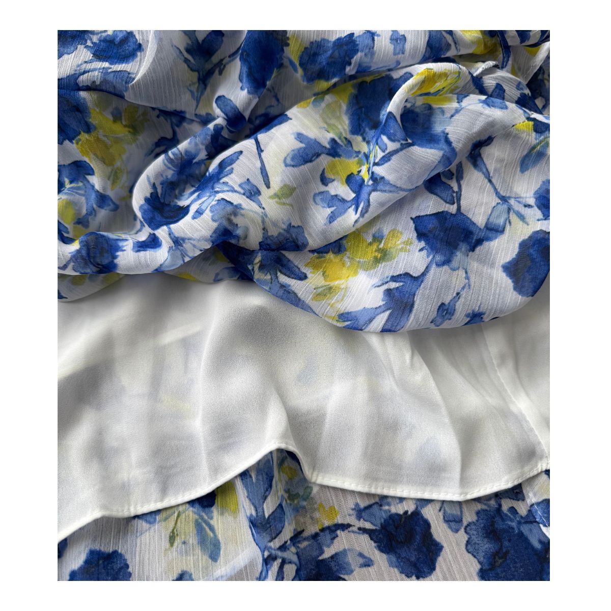 Vestido maxi floral en tonos oceánicos: capas de volantes vaporosos, estampado acuarela de flores índigo y amarillo sol sobre blanco puro. Cintura smocked y mangas flutter para un look cottagecore